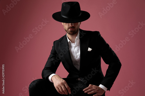 Serious looking dramatic man sitting and wearing tuxedo