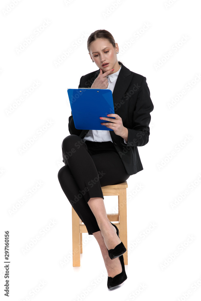 businesswoman sitting and reading something on clipboard intrigued businesswoman sitting and reading something on clipboard intrigued