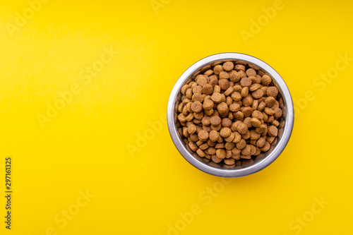 Dog food in a metal bowl. Yellow background photo