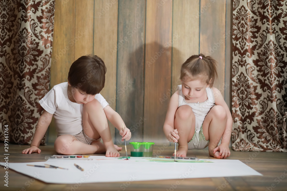 Little children paint on a large sheet of paper Little children paint on a large sheet of paper