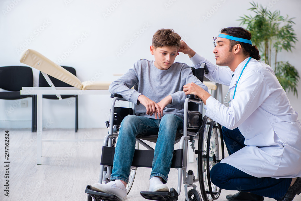 Young male doctor pediatrist and boy in wheel-chair Young male doctor pediatrist and boy in wheel-chair