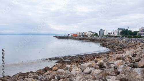 View of Salthill village & beach on a beautiful summer day, with rocks in the foreground. Near Galway Ireland