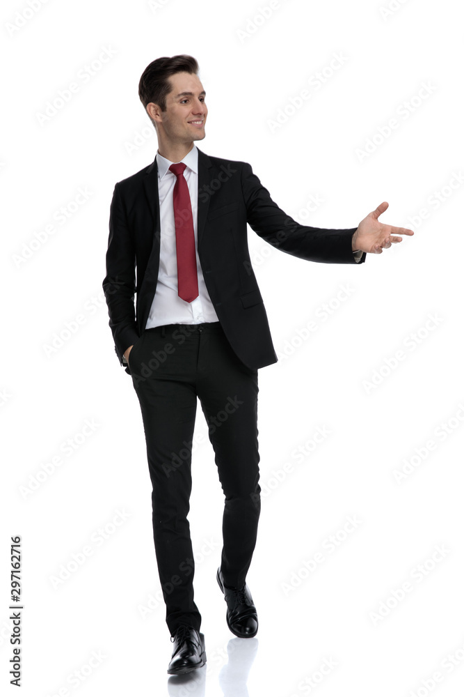 Positive young businessman presenting and smiling Positive young businessman presenting and smiling