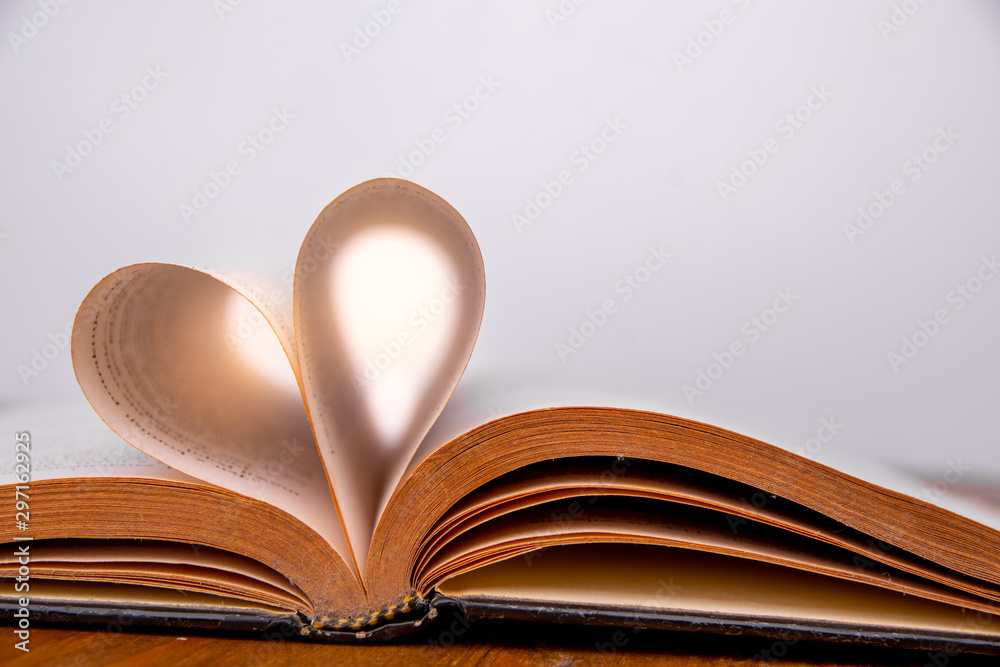 Old book and heart-shaped pages. White background. Wooden Table. Closeup. Copy space Old book and heart-shaped pages. White background. Wooden Table. Closeup. Copy space