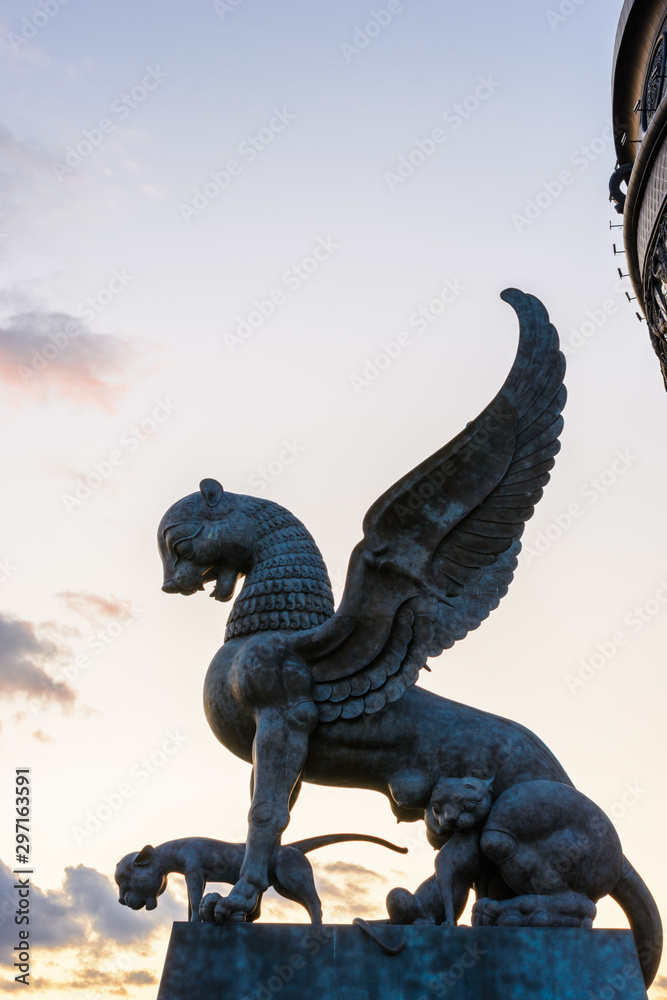 Fototapeta premium The sculpture female of winged snow leopard (Ak Bars, Aq Bars) with cubs, the symbol of Tatarstan near the Kazan wedding palace. Sunset.