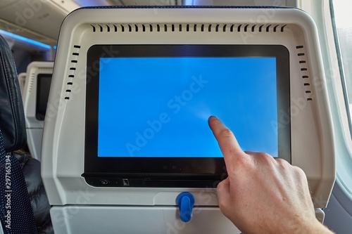 Using the seatback screen on a plane trip, watching movies, displaying flight data. Finger on blank touchscreen. photo