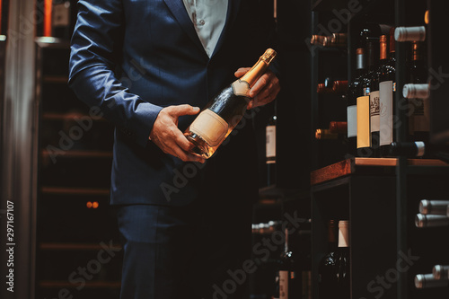 Elegant man in suit at wine cellar with bottle of wine