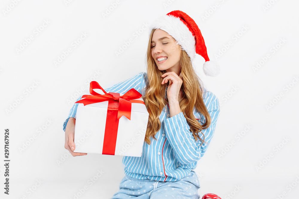Christmas morning. Happy beautiful young girl, in Christmas pajamas and Santa hat, opens Christmas gift Christmas morning. Happy beautiful young girl, in Christmas pajamas and Santa hat, opens Christmas gift