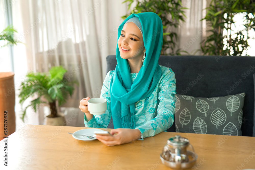 beautiful young woman in muslim dress is drinking tea in a restaurant beautiful young woman in muslim dress is drinking tea in a restaurant