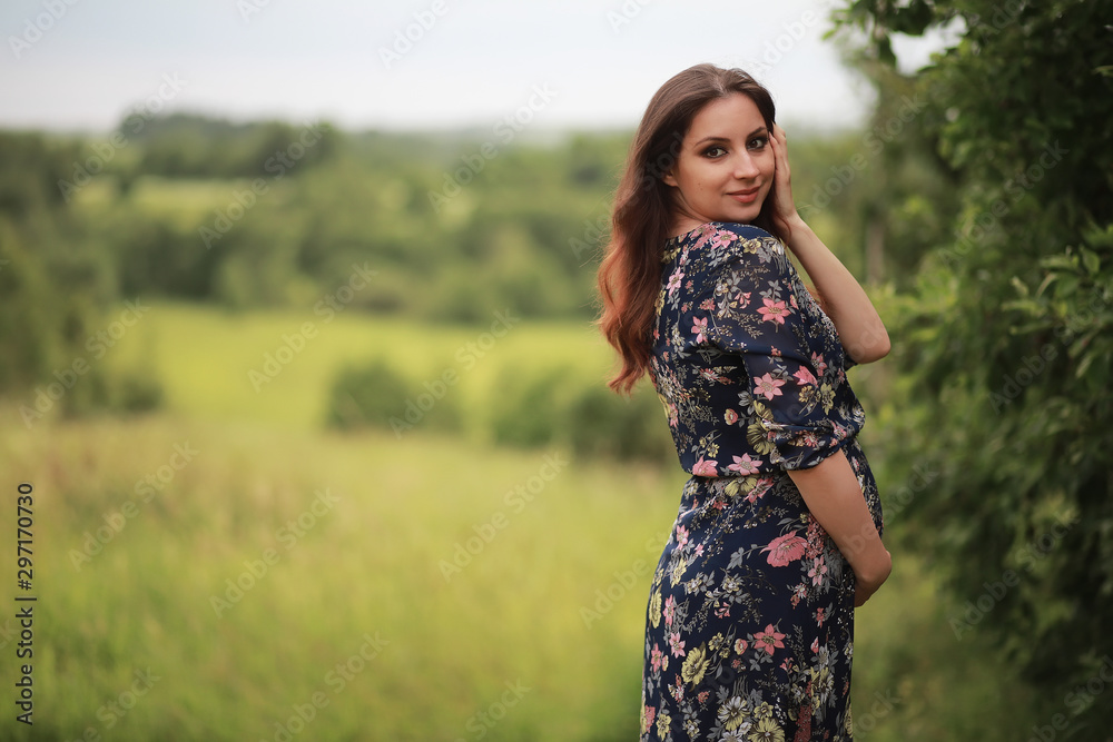 Fototapeta premium Pregnant girl in a dress in nature