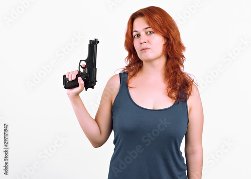 young redhead girl poses with her gun in her hand serious and threatening .Isolated on white background