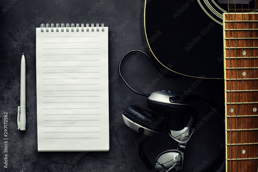 Fototapeta premium Guitar and accessories on a stone background. Desk musician, headphones, microphone.