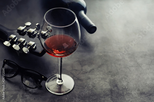 Canvas Print Guitar and high glass with red wine on a stone background.