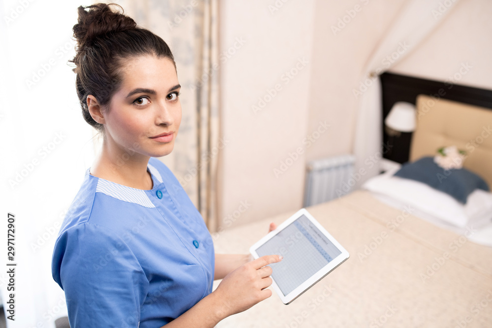 Pretty young chamber maid with touchpad working with electronic documents