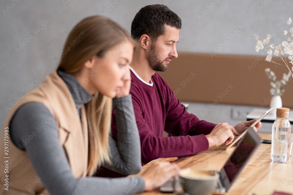 Obraz premium Serious young man with touchpad scrolling through electronic document