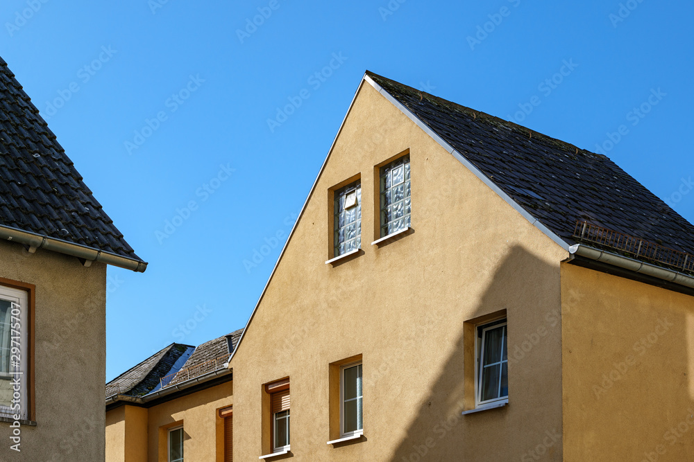 Outdoor view of typical style building with contemporary modern gamble roof, simple rectangular windows and yellow exterior facade, in europe. 