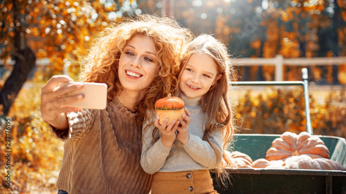 Young adult mother and daughter looking at carved pumpkin with smoke