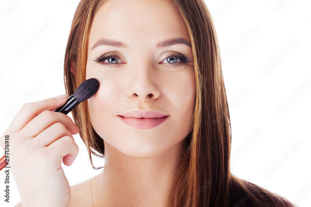 Use the powder. Attractive girl doing makeup. Portrait of a beautiful young woman using a brush for Foundation