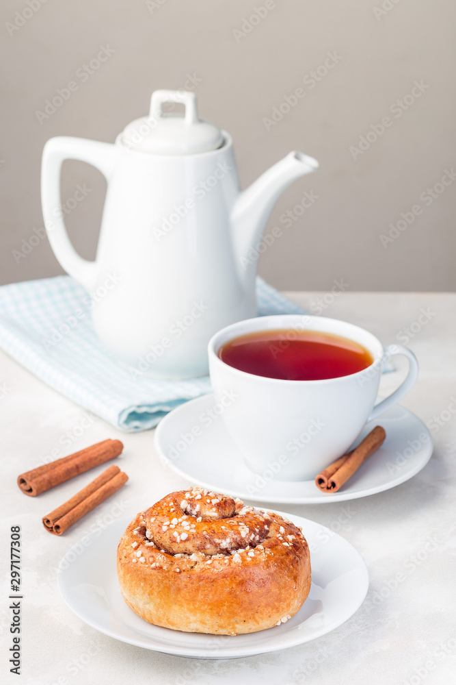 Cinnamon buns on white plate, served with a cup of red tea, vertical Cinnamon buns on white plate, served with a cup of red tea, vertical