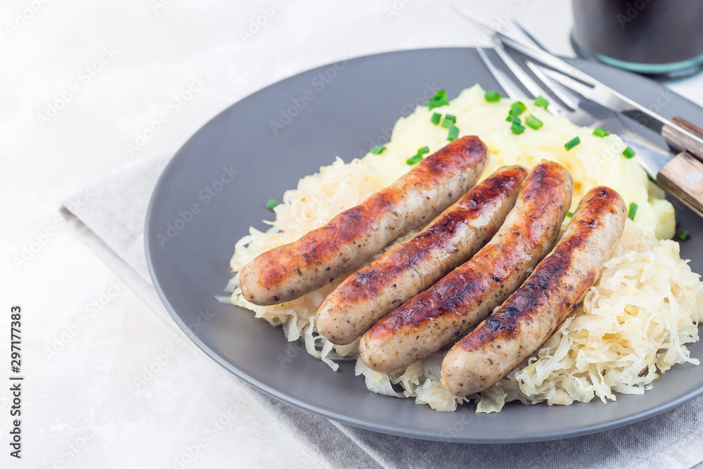 Roasted nuremberg sausages served with sour cabbage and mashed potatoes, on gray plate, horizontal, copy space Roasted nuremberg sausages served with sour cabbage and mashed potatoes, on gray plate, horizontal, copy space
