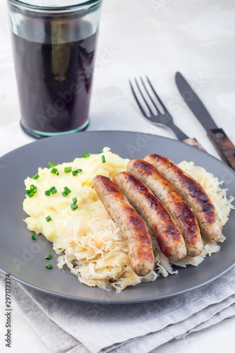 Roasted nuremberg sausages served with sour cabbage and mashed potatoes, on gray plate, vertical