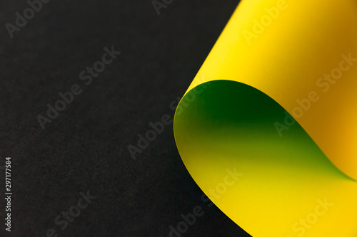 Lemon green and yellow gradient color curve shaped paper on plane black background