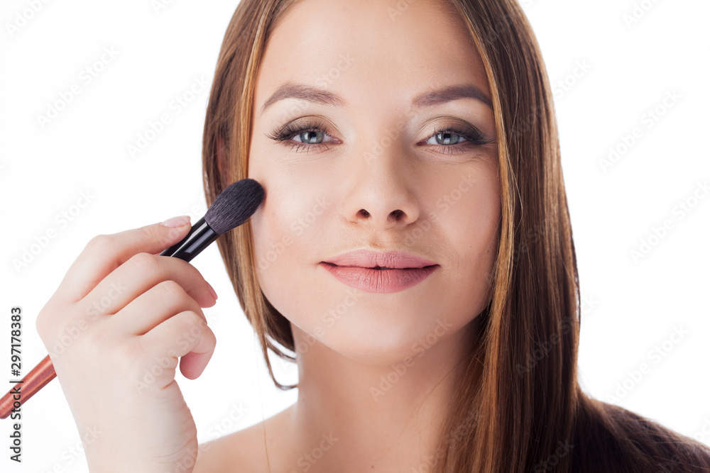 Use the powder. Attractive girl doing makeup. Portrait of a beautiful young woman using a brush for Foundation