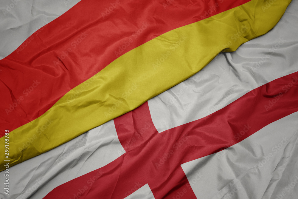 waving colorful flag of england and national flag of south ossetia. waving colorful flag of england and national flag of south ossetia.