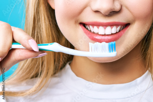 Young beautiful woman is engaged in cleaning teeth. Beautiful smile healthy white teeth. A girl holds a toothbrush. The concept of oral hygiene. Promotional image for a stomatology, dental clinic