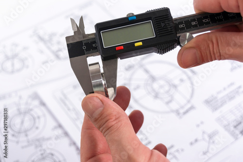 Tableau sur toile Measuring a steel part with a vernier caliper in a person’s hand