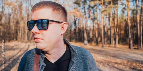 A man in sunglasses poses in the autumn forest
