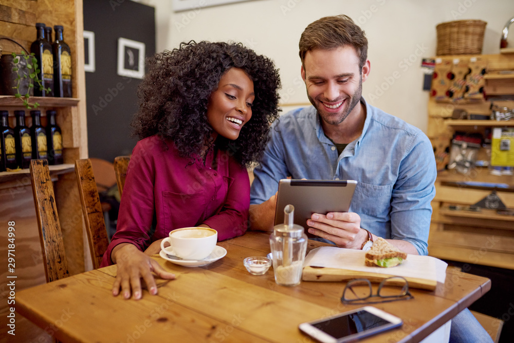 Obraz premium Diverse young couple using their tablet in a cafe