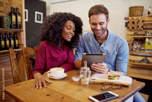 Diverse young couple using their tablet in a cafe