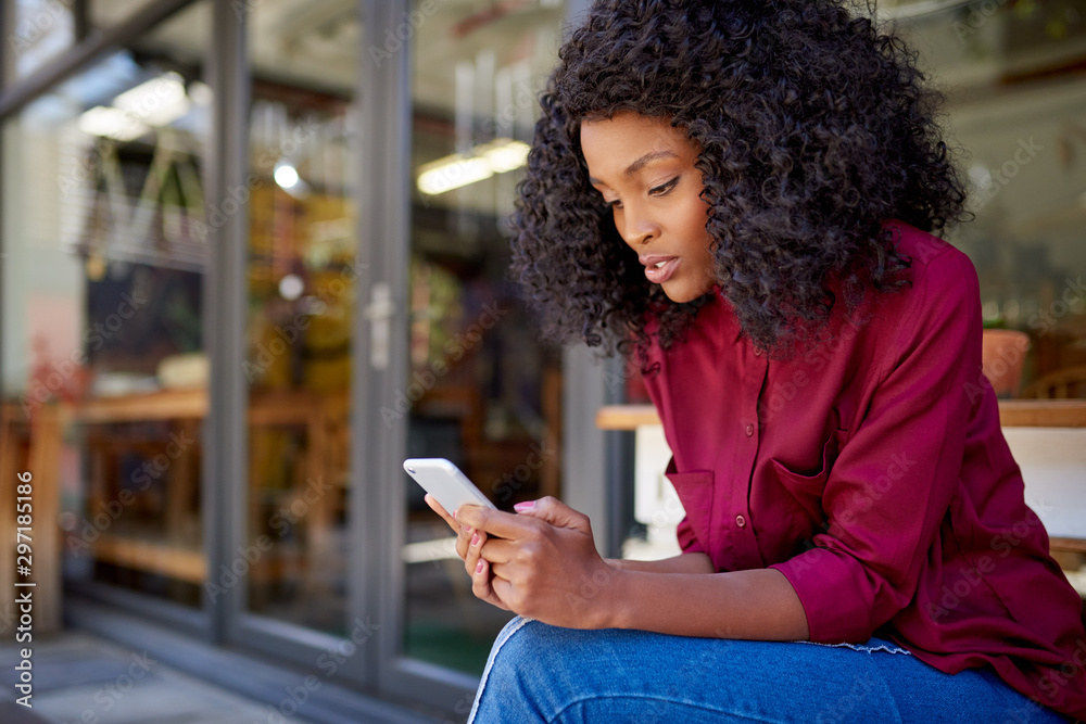 African American woman using her cellphone at a sidewalk cafe African American woman using her cellphone at a sidewalk cafe