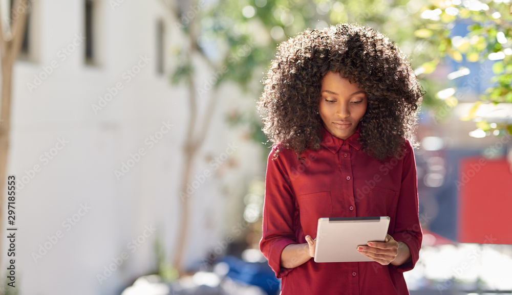 Young African American woman using a tablet in the city - obrazy, fototapety, plakaty 