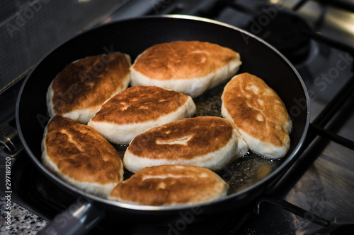 Fried pies in a pan standing on a gas stove