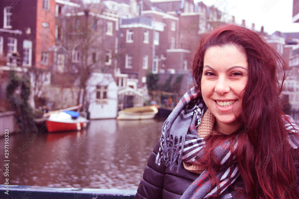 red-haired Caucasian girl in autumn or winter season dressed in warm clothes for the cold between the streets of Amsterdam