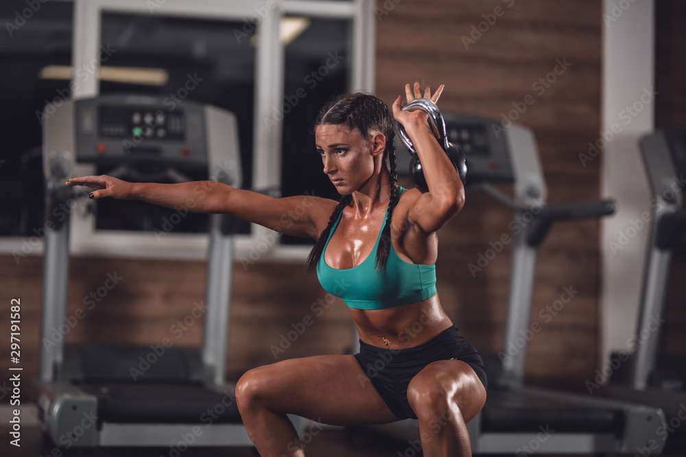 Fototapeta premium Strong girl exercise withe kettle-bell in the gym