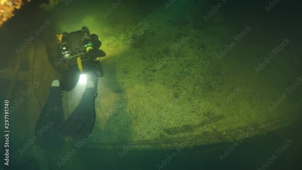 Diving inside shipwreck in underwater submarine world of ships from World War II as result of military battles on Truk Islands. Concept of diving in historic underwater sites of sunken wreck.