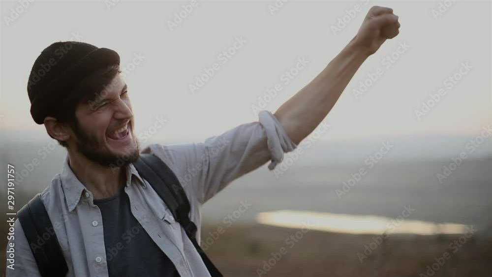Portrait of excited hipster guy, traveler on background of sunset, wearing shirt, black beanie hat and backpack. Portrait of excited hipster guy, traveler on background of sunset, wearing shirt, black beanie hat and backpack.