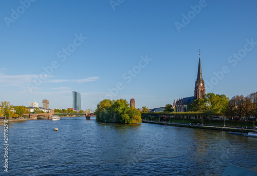 Outdoor sunny view from Eiserner Steg, Iron Bridge, of promenade on riverside of Main River and background of European Central Bank in sunny day in Frankfurt, Germany.