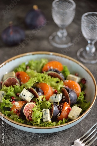 Healthy salad of persimmons, figs, blue cheese, pomegranate seeds, parmesan, lettuce and olive oil.