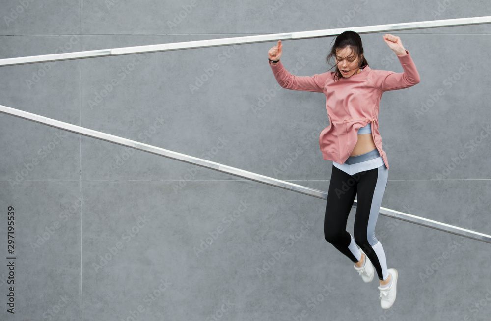 An athletic young woman is jumping, doing acrobatics, ballet, is actively involved in sports, against a concrete wall. An athletic young woman is jumping, doing acrobatics, ballet, is actively involved in sports, against a concrete wall.