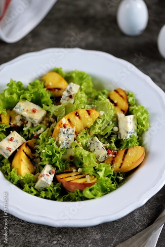 Grilled peach salad with lettuce, blue cheese, parmesan, olive oil and pink pepper.