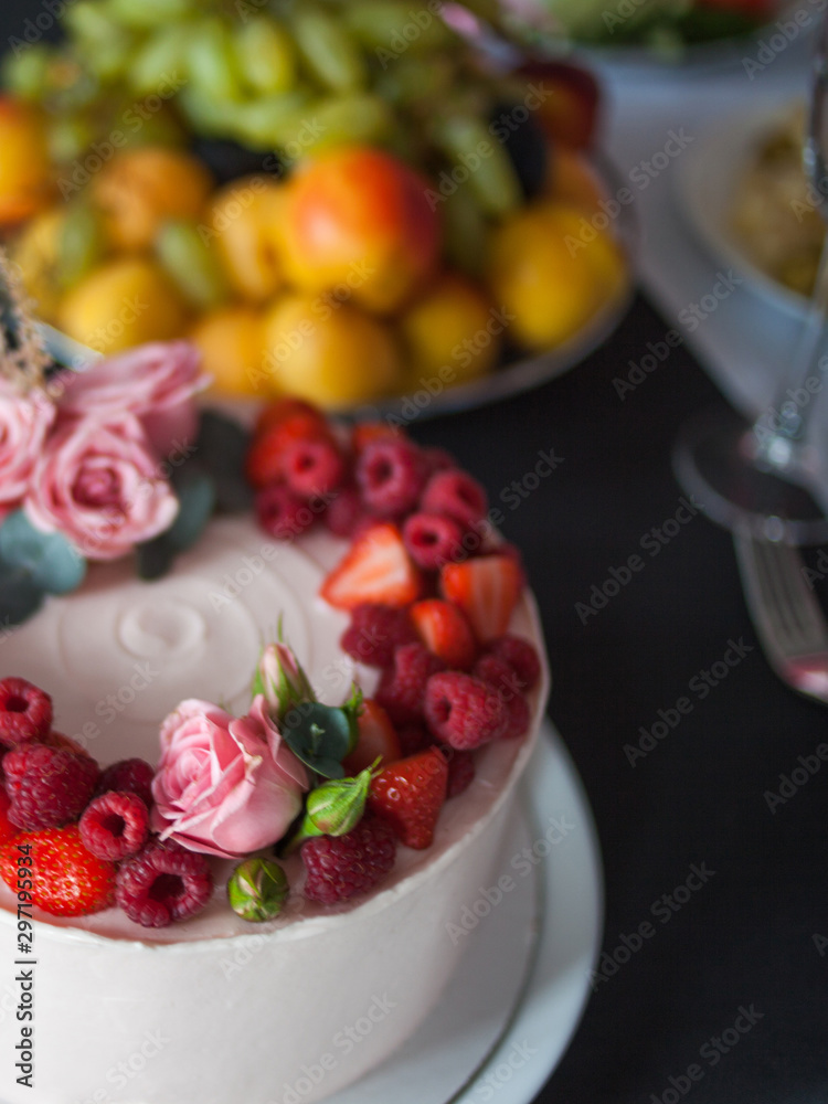 Delicate and delicious pink cake with cream and berries. Beautiful birthday cake on the table,