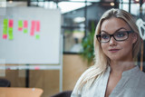 Young confident business woman in glasses on the background of the workspace.