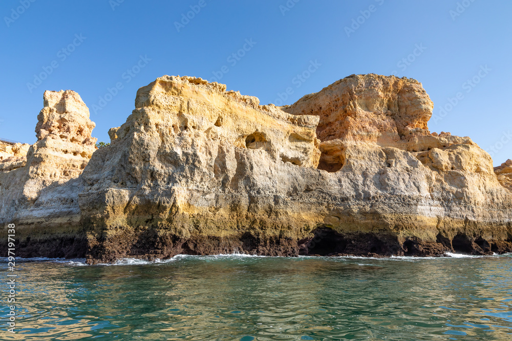 Beautiful landscape of Algarve, Portugal coast with sandstone cliffs, beach and ocean under cloudless blue sky