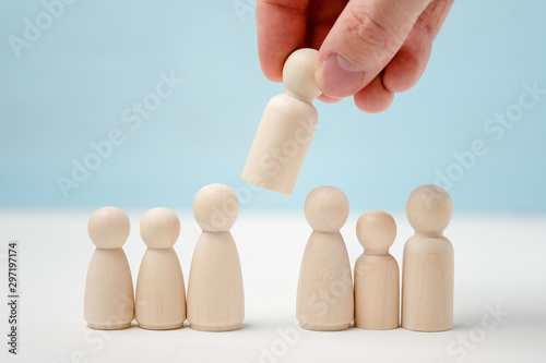 Принти на полотні Hand puts or removes wooden figure in the center of figures lined up