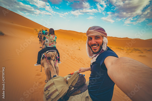 happy nomad man taking crazy selfie during camel riding in Sahara Desert, Merzouga, Morocco