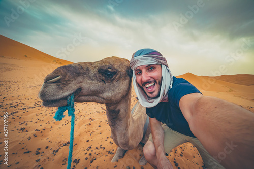 Photography happy nomad man taking crazy selfie during camel riding in Sahara Desert, Merzou